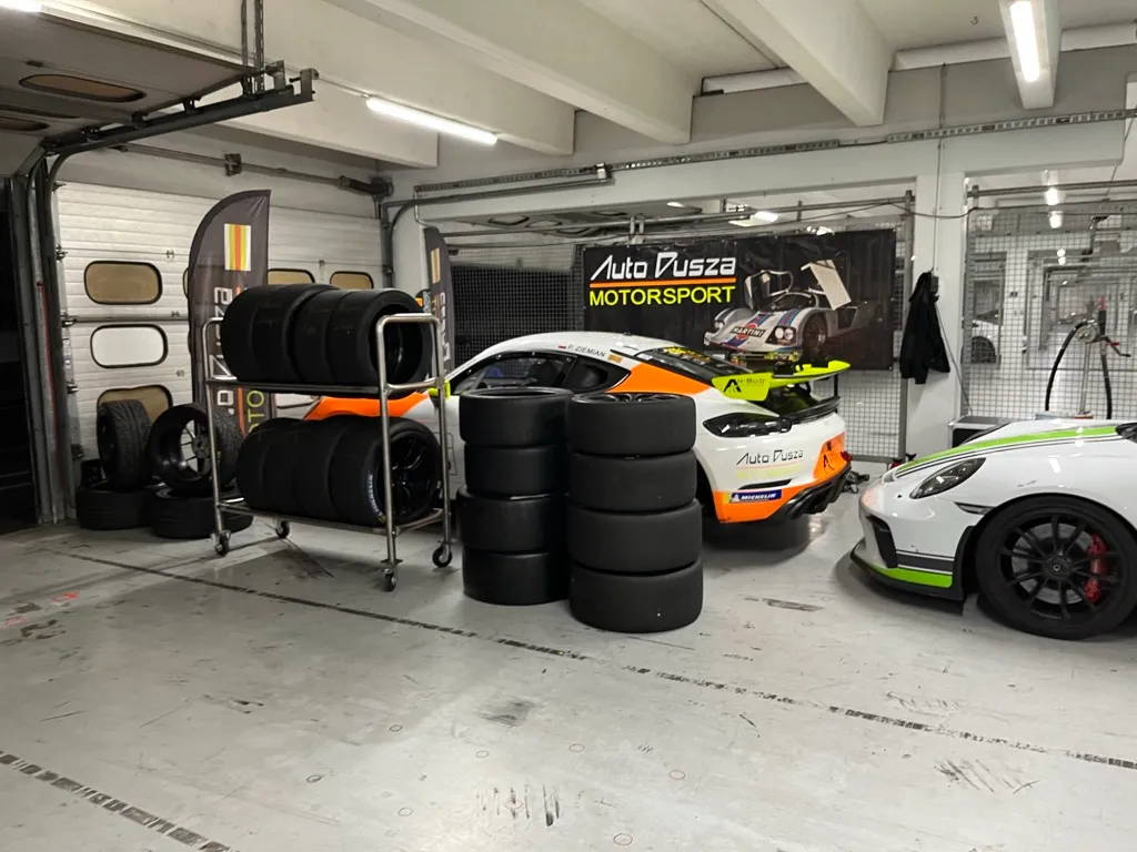 Box serwisowy Auto Dusza Motorsport z kompletami opon i wyścigowym Porsche