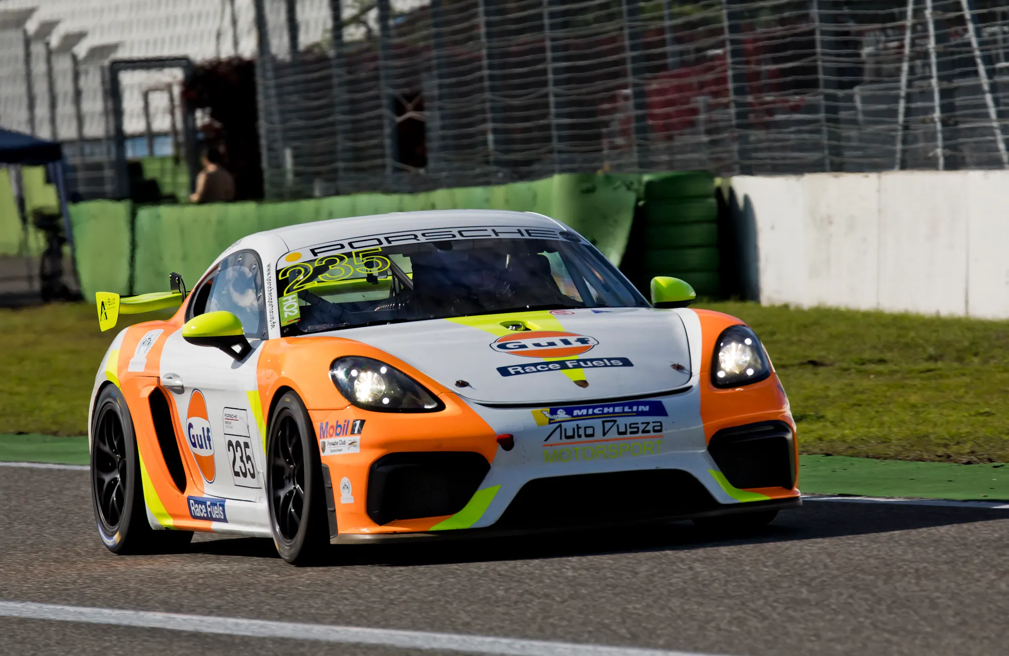 Porsche 718 Cayman GT4 w barwach Auto Dusza Motorsport podczas przejazdu po torze wyścigowym