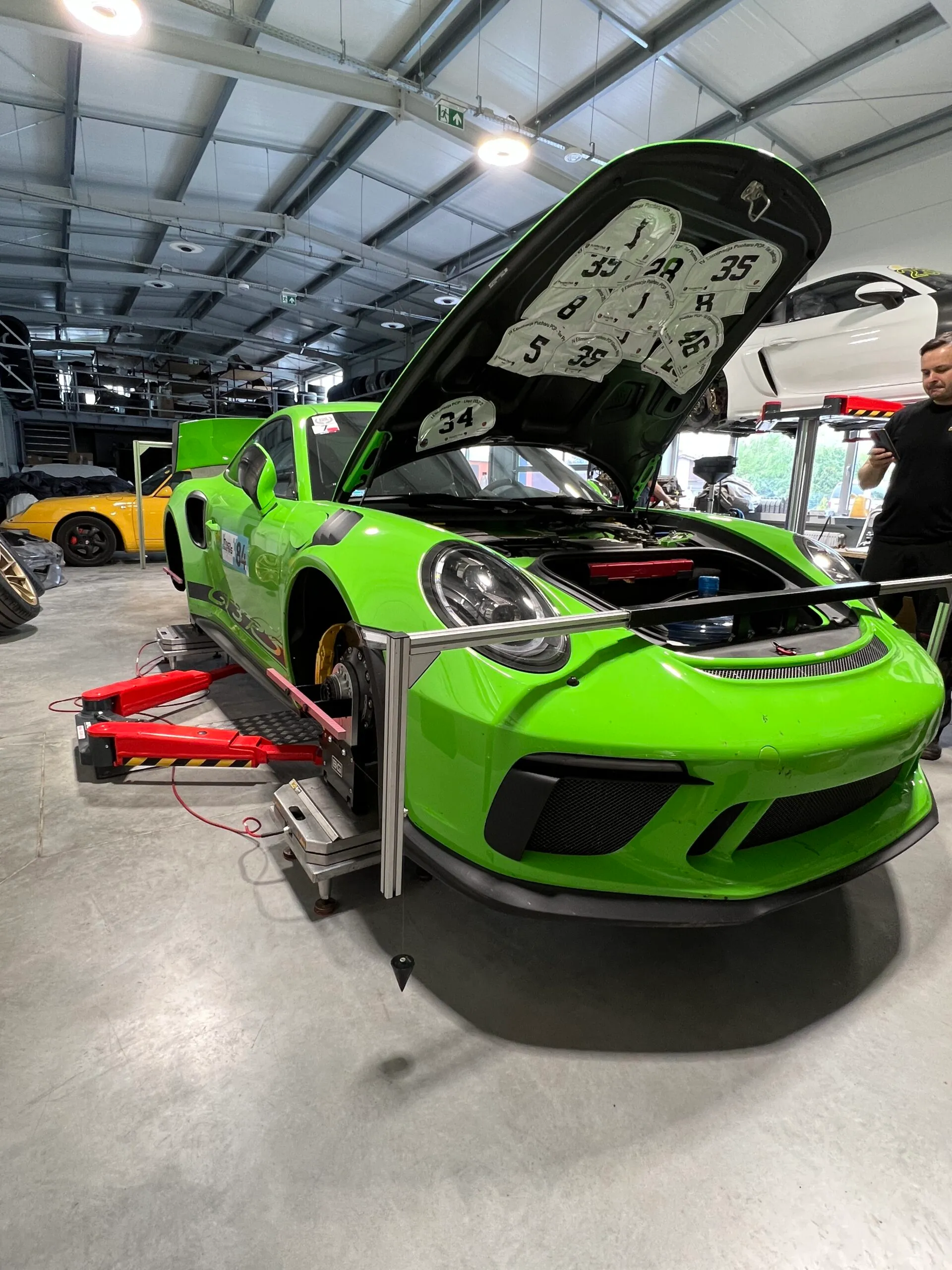 Zielone Porsche na stanowisku serwisowym z otwartą pokrywą przednią