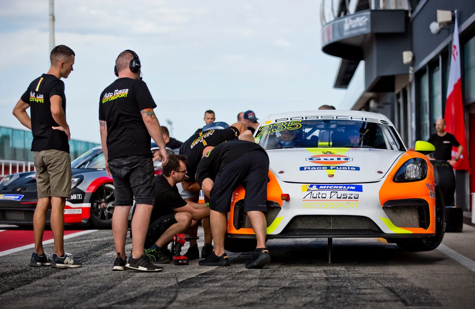 Mechanicy i kierowca przy wyścigowym Porsche przed startem